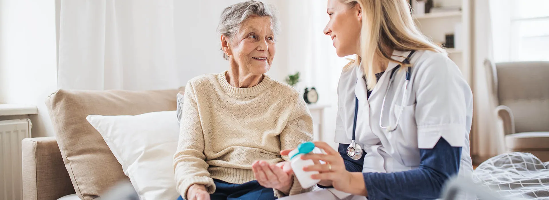 old woman and nurse sitting on bed 